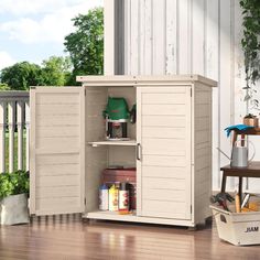 an outdoor storage cabinet with its doors open on the deck next to a potted plant