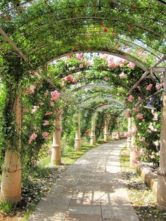 an archway covered in pink flowers and greenery