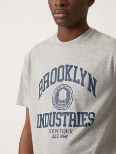 Our tribute tee is made from soft premium cotton, giving it a luxe, midweight drape. With Brooklyn Industries printed across the chest, an embroidered crest, and a relaxed fit, it's a comfy classic with character. #B0612120-80018 Fabric: 50% cotton, 50% polyester Crew Neck Logo T-shirt For Loungewear, Gray Cotton T-shirt For Loungewear, Heather Grey Cotton T-shirt For Loungewear, Trendy Heather Grey T-shirt With Letter Print, Casual Heather Grey T-shirt For Loungewear, Classic Cotton T-shirt With Letter Print, Gray Crew Neck T-shirt For College, Sporty T-shirt With Embroidered Graphics And Relaxed Fit, Sporty Relaxed Fit T-shirt With Embroidered Graphics