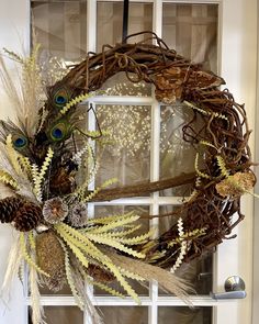 a wreath made out of twigs and feathers on a window sill with a glass door in the background