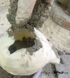 a close up of a person's hand with mud on it and cement in the middle