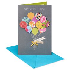 a happy birthday card with balloons and ribbons on the front, sitting on top of a blue envelope