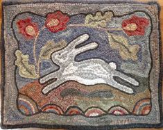 a rug with a white rabbit in the middle and flowers on it's side