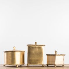 three brass canisters with lids on wooden table