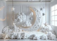 a room decorated in white with stars, moon and clouds on the wall above it