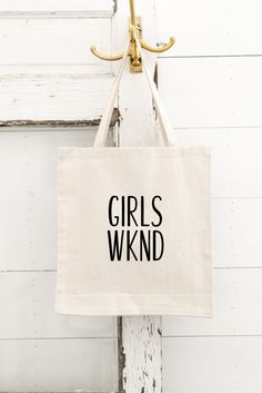 a tote bag that says girls wknd hanging from a hook on a door