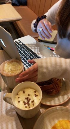 a woman sitting at a table with a laptop and cup of coffee in front of her