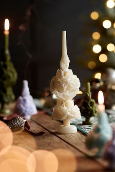 a table topped with candles and small christmas trees on top of wooden tables covered in lights