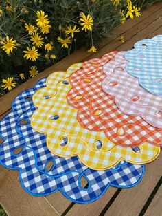 four place mats sitting on top of a wooden table next to yellow and white flowers