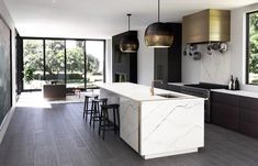 a modern kitchen with marble counter tops and wooden floors