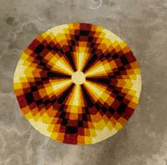 an orange, yellow and black circular rug on the ground