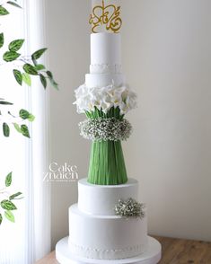 a white and green wedding cake with flowers on top