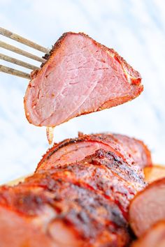 a piece of meat is being lifted by a fork from a plate with ham on it