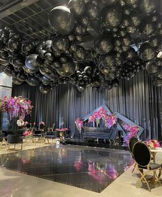 a room filled with black and white balloons hanging from the ceiling over a piano surrounded by chairs