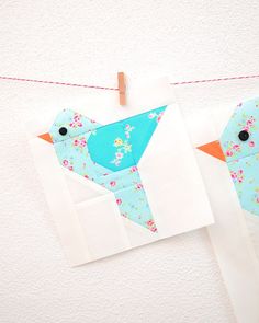 two paper birds are hanging on clothes pins