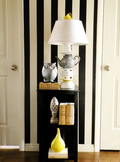 a black and white striped wall in a living room with a lamp on top of it