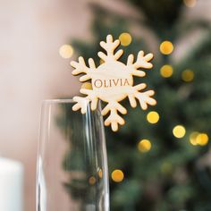 a wooden snowflake sitting on top of a glass next to a christmas tree