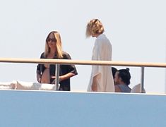 two women standing on top of a boat next to each other with one woman in the background