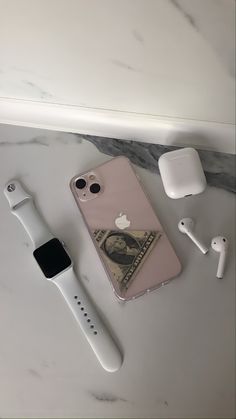 an apple watch, headphones, and money on a counter