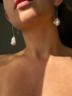 a close up of a woman wearing earrings and looking off into the distance with her eyes closed