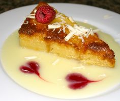 a piece of cake on a plate covered in cream and raspberry toppings