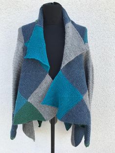 a blue and gray knitted shawl sitting on top of a mannequin