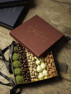 a box filled with assorted chocolates and nuts on top of a wooden table