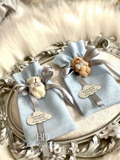 two teddy bears wrapped in blue and grey ribbon on a silver tray with white fur