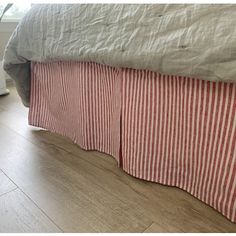 a bed with red and white striped bedspread next to a potted plant