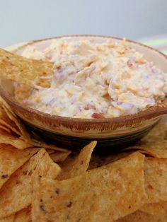 a bowl filled with dip surrounded by tortilla chips