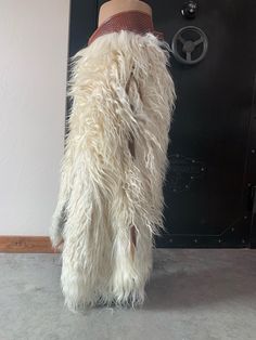 a white furry animal with a hat on its head standing in front of a door