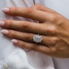 a woman's hand with a diamond ring on her left hand, wearing a white shirt