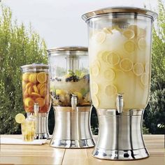 three different blenders sitting on top of a wooden table next to trees and bushes