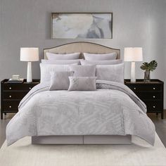 a bed with grey and white comforter in a bedroom next to two nightstands