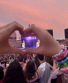 a person making a heart shape with their hands in front of an audience at a concert