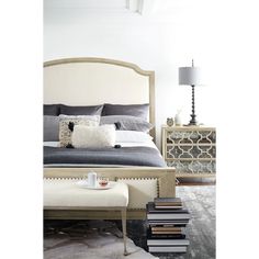 a bedroom with a bed, night stand and several books stacked on the nightstands