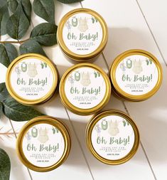 four small gold tins filled with baby's breath lotion on top of green leaves