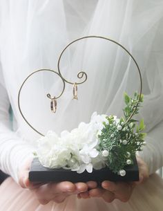 a person holding flowers in their hands with a ring on it's head and an earring hanging from the back