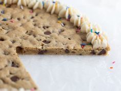 a chocolate chip cookie with white frosting and sprinkles is cut in half