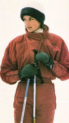 a woman standing in the snow wearing skis