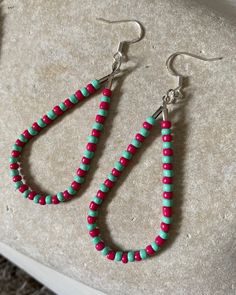 two pairs of beaded earrings sitting on top of a stone slab next to each other