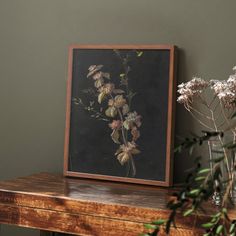 some flowers are sitting on a table next to a vase with dried flowers in it