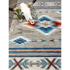 a rug with an animal skull on it and cactus in the corner next to it