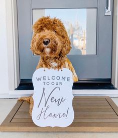 a dog is holding a sign that says welcome to your new home on the front door