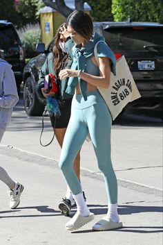 two women walking down the street with shopping bags in hand and one woman wearing blue leggings