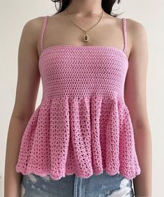 a woman wearing a pink crochet top with short shorts and a gold necklace