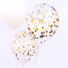 three white balloons with gold confetti on them