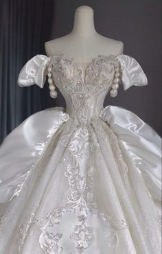 a white wedding dress with pearls on the shoulders