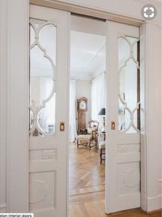 an open door leading into a living room with hardwood floors and white walls in the background