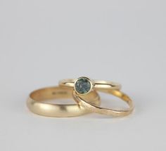 two gold wedding rings with a green diamond